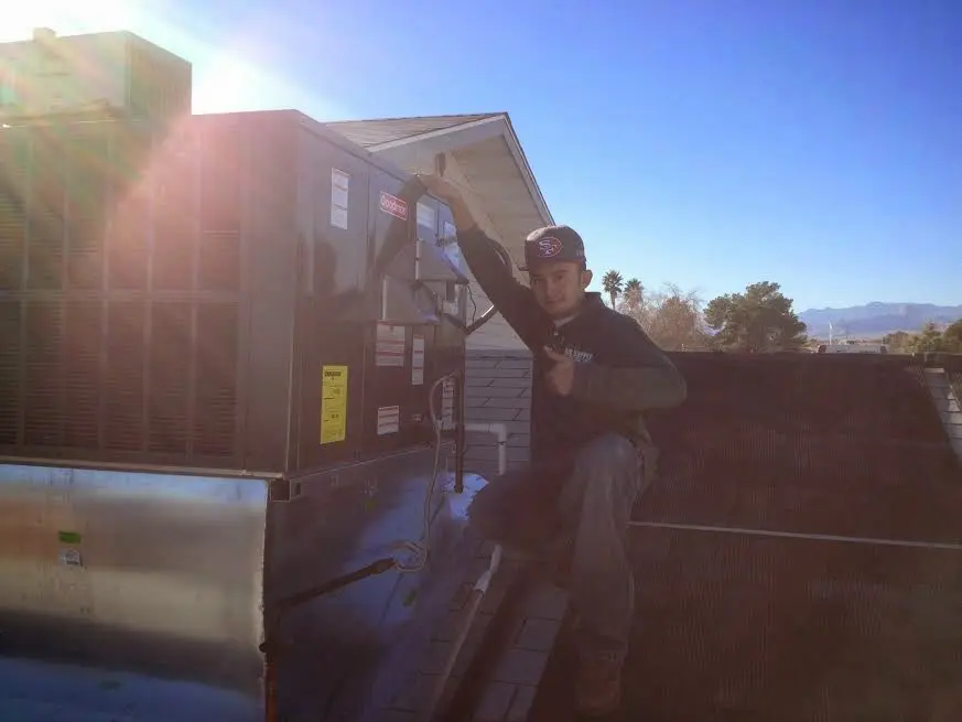 HVAC technician performing Heat Pump Repair on a rooftop unit in Manor